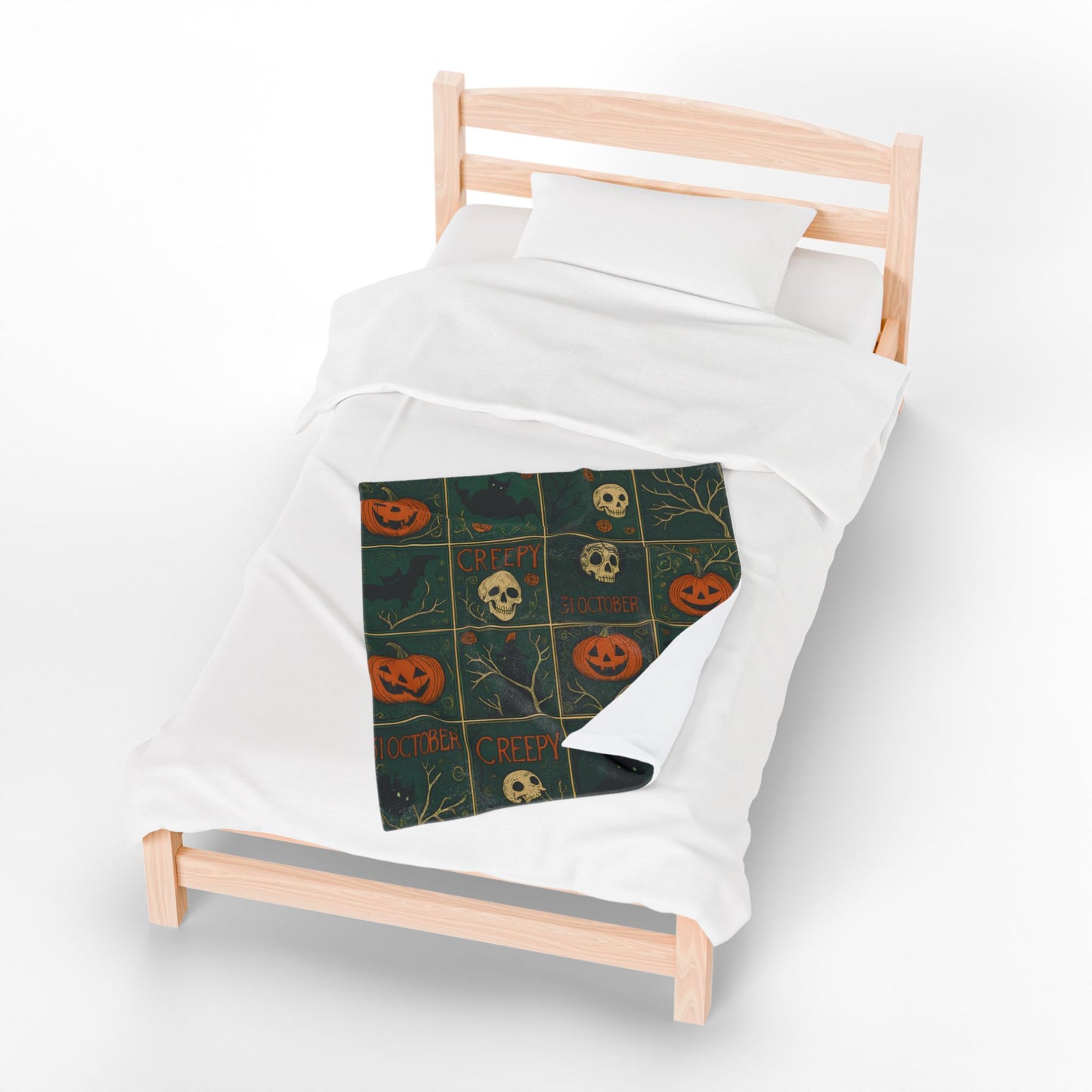 Halloween-themed blanket with pumpkins and skulls on a white bed with wooden headboard