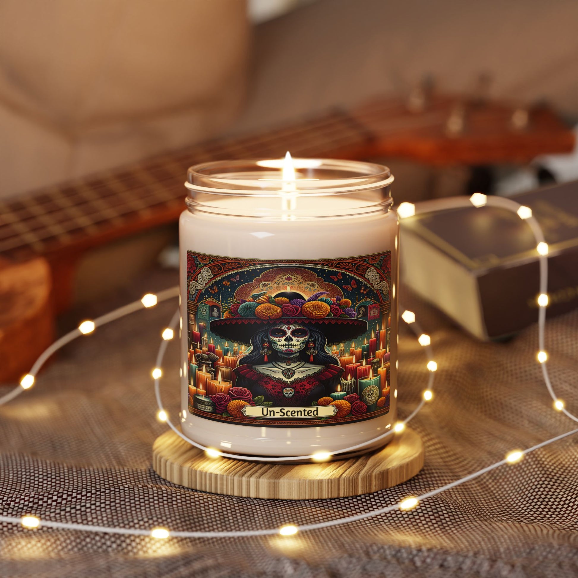 Candle with a colorful label featuring a skeleton in a sombrero on a wooden coaster with string lights.