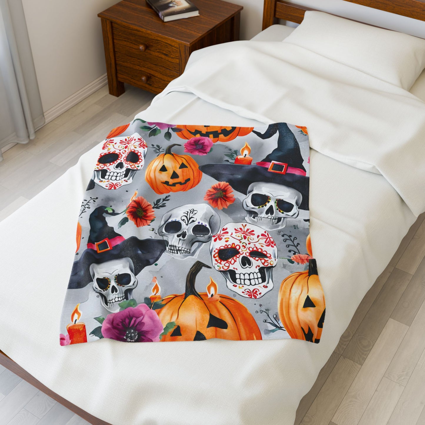 Halloween-themed blanket with skulls, pumpkins, and witches on a bed.