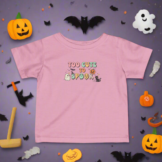 Pink t-shirt with 'Too Cute to Spook' text and graphics on a white background