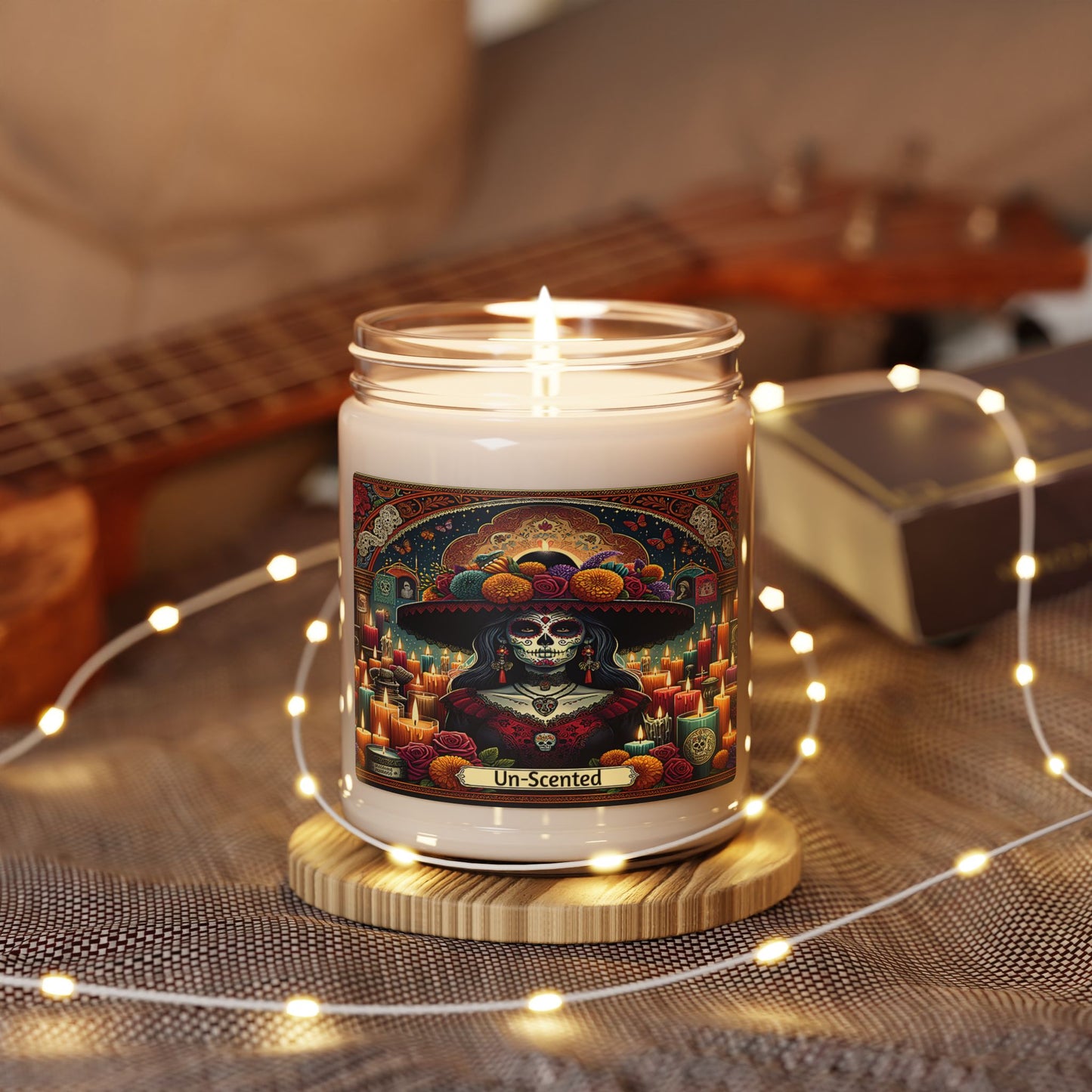 Candle with a colorful label featuring a skeleton in a sombrero on a wooden coaster with string lights.